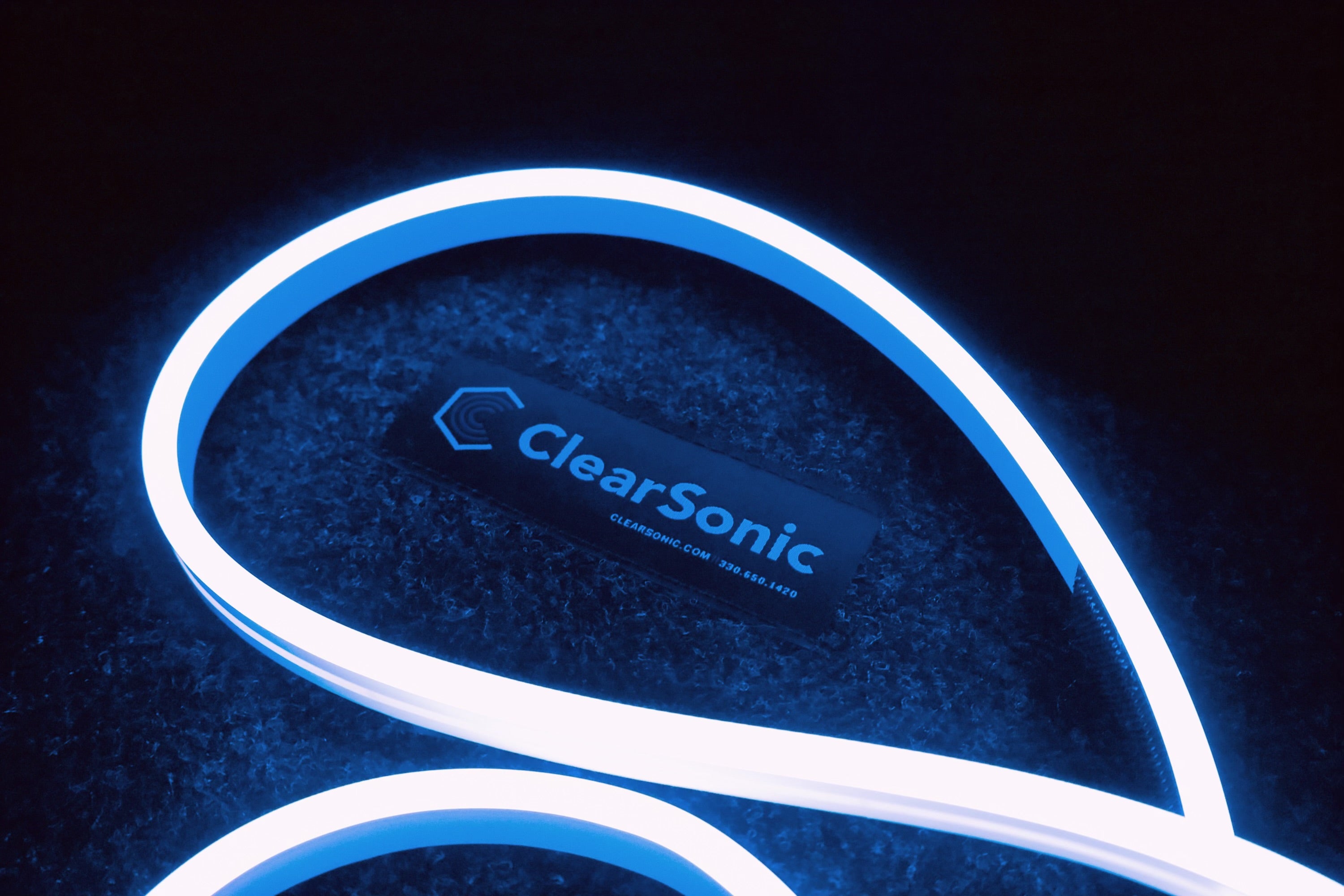 A coiled blue LED light with a 'ClearSonic' logo illuminated on it, against a dark background.