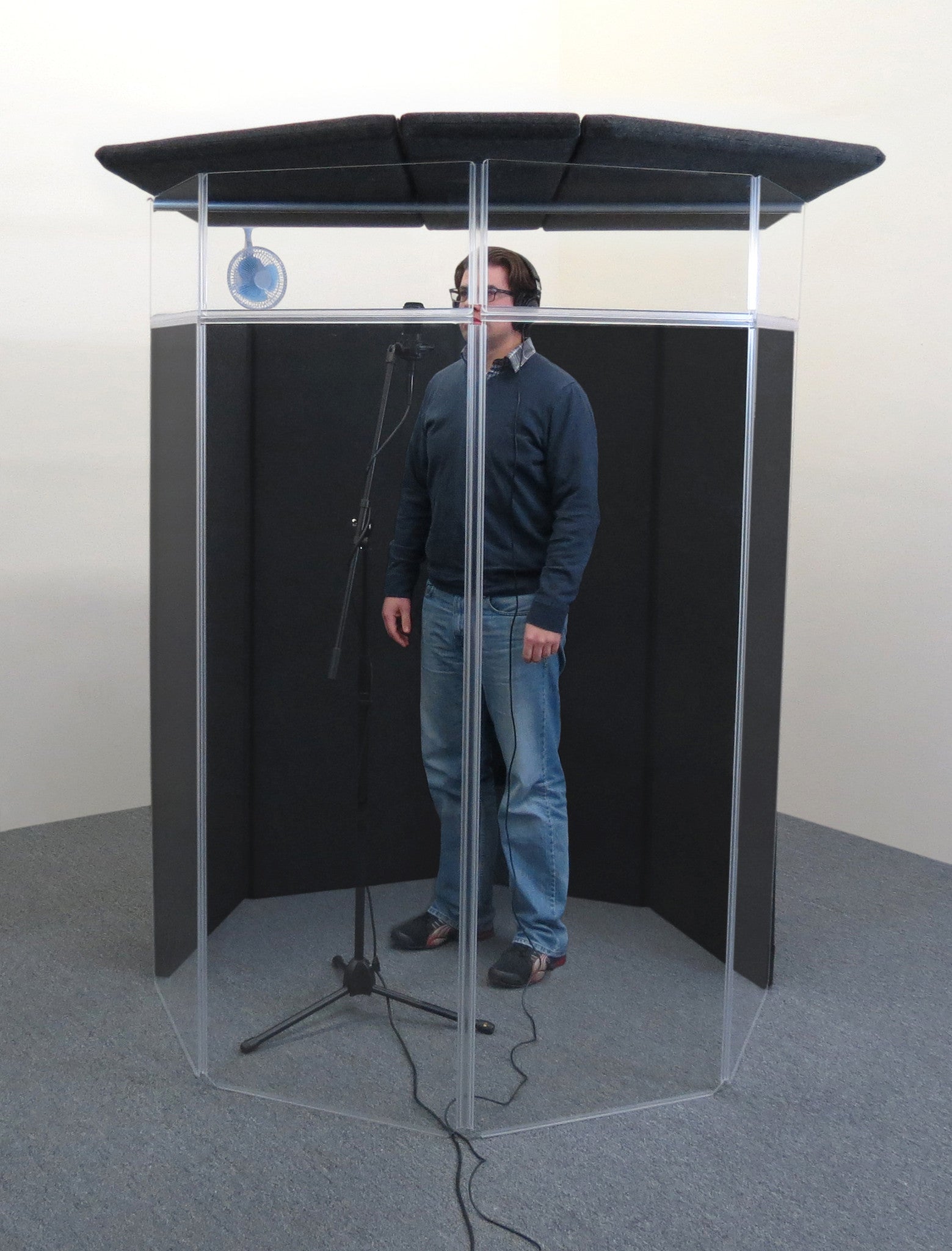A person recording voiceovers inside an IsoPac F vocal booth.